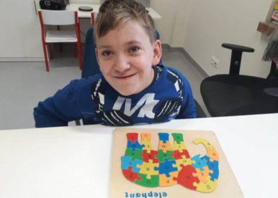 Uśmiechnięty chłopaka układa puzzle.