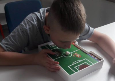 Chłopak gra w piłkarzyki, dmuchając ustami w kostkę do gry.